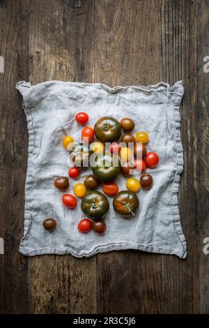 Gemischte Tomatensorten auf einem Leinentuch auf einer Holzfläche Stockfoto