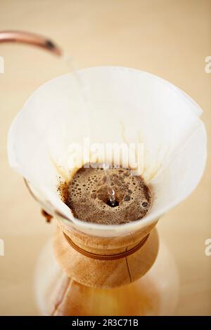 Heißes Wasser wird über Kaffee in einem Glas chemex gegossen Stockfoto