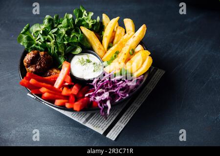 Bunte Gemüseschüssel mit Kartoffelkeilen und veganen „Fleischbällchen“ Stockfoto