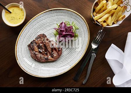 Ein Steak mit Meersalz und einer Seite eingelegter Gurken, lila Kohl und Pommes Stockfoto