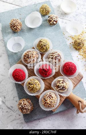 Gesunde Dattel- und Schokoladenpralinen mit Erdnüssen, Mandeln, getrockneten Himbeeren und Pistazien Stockfoto