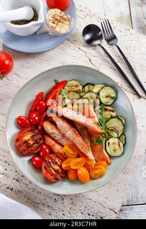 Gebackene Lachsstücke serviert mit gegrilltem Gemüse Stockfoto
