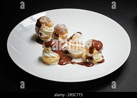 Profiteroles mit Schokoladensoße bespritzt Stockfoto