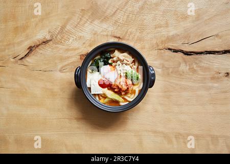 Ramen mit udon-Nudeln, Kimchi, Huhn, Käse, Ei, Algen und Enoki-Pilze Stockfoto
