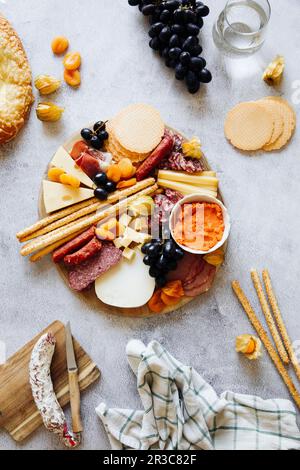 Käseplatte mit Crackern, Grissini, Salami und Trauben Stockfoto