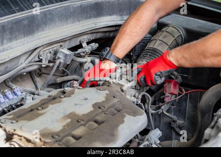 Autoreparaturen. Der Automechaniker trennt die Luftleitung vom Fahrzeugmotor. Stockfoto