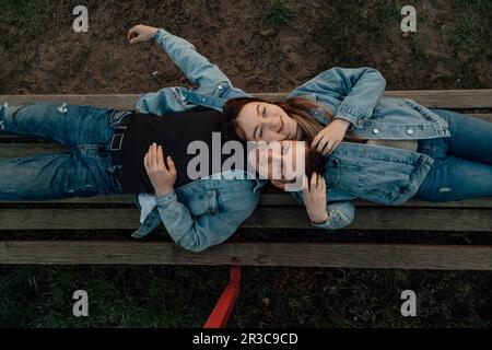 Glückliches junges, liebevolles Paar, das sich auf der Bank im Park entspannt Stockfoto