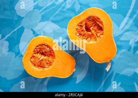 Frischer Butternusskürbis auf blauem Hintergrund. Butternusspüree. Hälften rohen Orangenkürbis. (Fortsetzung Stockfoto