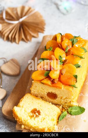 Orange Pound Cake mit frisch gepresstem Orangensaft und Orangenschale, dekoriert mit getrockneten Aprikosen, Minzblättern und Mandeln. Stockfoto