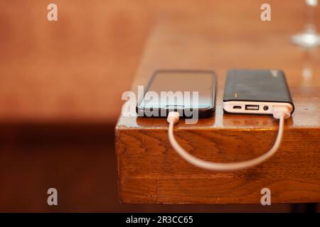 Smartphone laden mit Power Bank auf Holz board Stockfoto