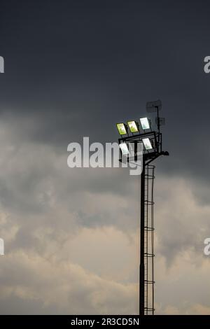 Helle Sportstadion-Lichter an einem bewölkten Abend Stockfoto