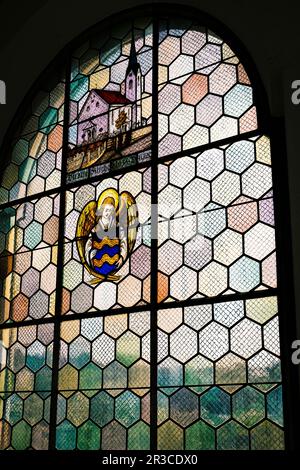 Ein wunderschön gestaltetes Fenster mit farbigen Glasstücken, die von Blei zusammengehalten werden, wodurch faszinierende Muster entstehen und lebendiges Licht durchdrungen wird. Stockfoto