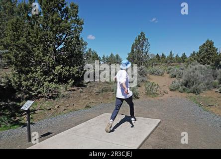 Eine Studentin, die auf dem Pine Nursery Course in Bend, Oregon, Disc Golf spielt. Stockfoto