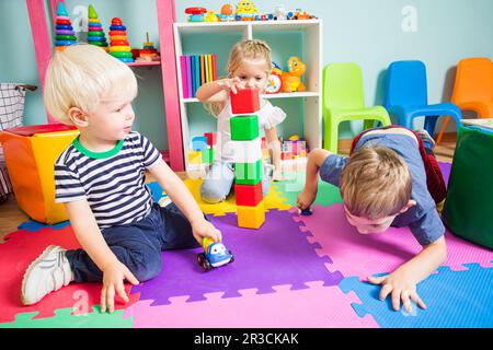 Die Kinder spielen mit verschiedenen Spielsachen im Spielzimmer Stockfoto