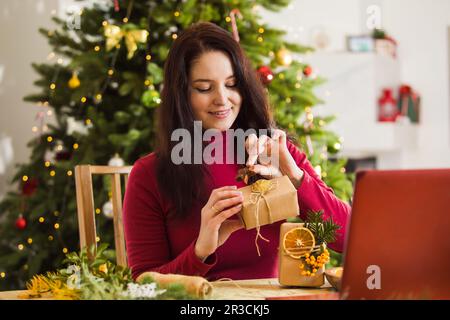 Frau zeigt, wie man Weihnachten Öko gestylte Geschenke verpackt Stockfoto