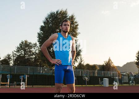 Der junge Mann, der für das Laufrennen trainiert, beginnt draußen auf einer Stadionbahn Stockfoto