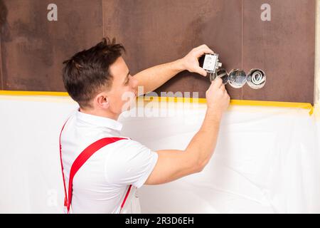 Der Elektriker repariert elektrische Leitungen für die Steckdose Stockfoto