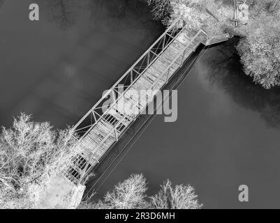 Flüstern der Geschichte widerspiegeln sich durch die Zeit, während eine alte Brücke den Fluss anmutig überquert, ihr verwitterter Charme erzählt Geschichten vergangener Tage. Stockfoto