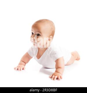 Liebenswert krabbelnd Baby Junge schaut beiseite auf weiß Stockfoto