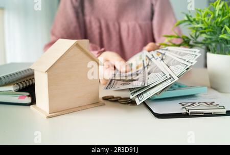 Nahaufnahme von Händen, die Hausmodell für Geld geben Stockfoto
