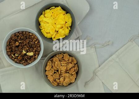Auswahl an Frühstückszerealien und Müsli in Schüsseln auf hellem Holzhintergrund. Fastfood. Draufsicht. Platz für Text. Stockfoto