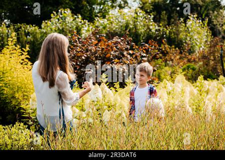 Mutter lehrt ihren Sohn im Garten spazieren zu gehen Stockfoto