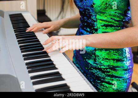 Die junge Frau spielt im Studio auf einem Synthesizer Stockfoto