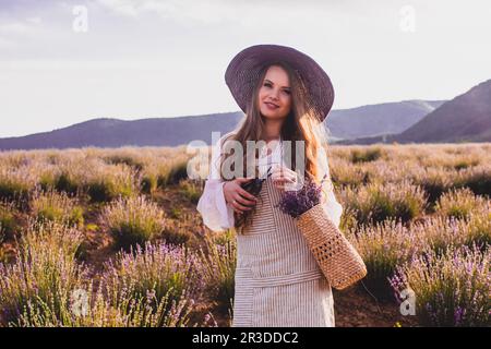Das schöne Mädchen ruht moralisch auf einer Plantage beim Lavendel pflücken Stockfoto
