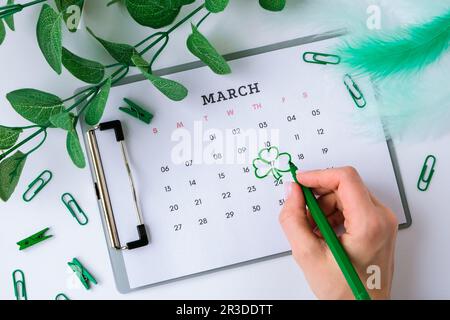 Kalender 17. März. Tag der Heiligen Patricks. Cleveres Blatt. Grüne Farben. Weibliche Hand plant Urlaub. Flach verlegt. Draufsicht. Stockfoto