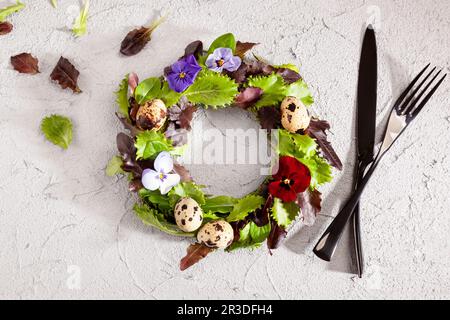 Kranz aus Salatblättern, Blumen und Eiern von oben. Stockfoto