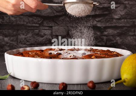 Puderzucker fällt auf Schokoladen-Haselnusskuchen. Stockfoto