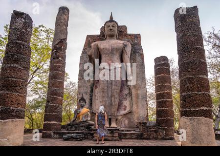 Touristin vor dem riesigen stehenden Buddha im Tempel Wat Saphan hin, UNESCO Welterbe Geschichtspark Sukhothai, Thailand, Asien | weibliche Touristen aus Stockfoto