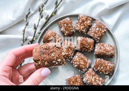 Weiblicher Handgriff, Haferkekse, Hafer geht mit Energie, selektive Fokussierung. Vegane Süßigkeiten. Hausgemachte Bäckerei. Rohes, veganes, gesundes Dessert für Stockfoto