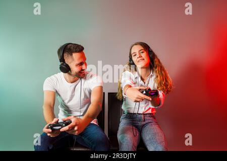 Fröhliche Freunde, die Joysticks halten und mit dem virtuellen Spiel beginnen Stockfoto