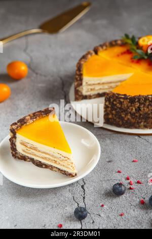 Käsekuchen mit Mangofrucht auf grauem Hintergrund. Käsekuchen mit Passionsfruchtsauce auf der Oberseite dekoriert mit Beeren und Obst Stockfoto