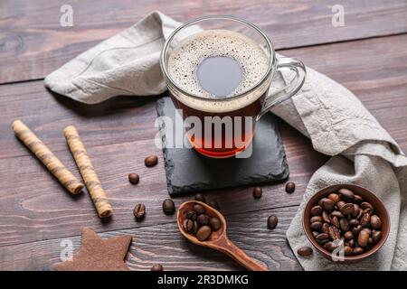 Trinken Sie Untersetzer mit einer Tasse Kaffee, Waffeln und Bohnen auf einem Holztisch Stockfoto