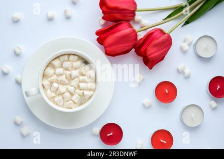 Platz für Text kopieren. Rote Tulpen Kerzen Weiße Tasse Kakao Marshmallows Frühstück. Urlaubshintergrund. Grußkarte. Va Stockfoto