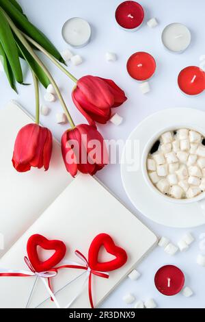 Modell mit leerem Bereich für Text. Rote Tulpen Kerzen Weiße Tasse Kaffee Frühstück. Urlaubshintergrund. Grußkarte. Stockfoto