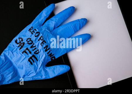 Aufgeblasener blauer Latex-OP-Handschuh auf schwarzem Hintergrund. - Ich öffne den Covid-Safe wieder. Öffnen Sie wieder Text auf medizinischen Handschuhen. Neue Norm Stockfoto