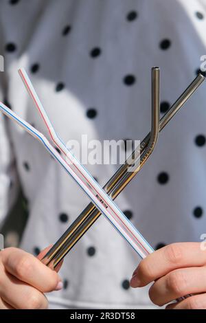 Frau mit wiederverwendbaren Metall- und Plastik-Trinkhalmen. Weibliche Hand auf wiederverwendbarem zusammenklappbarem Trinkhalm. Umweltfreundlicher Lifestyle und Stockfoto