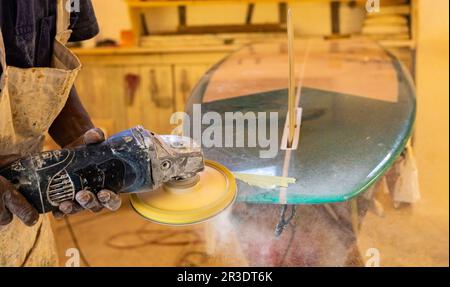 Ein afrikanischer Craftsman Surfboard Shaper, der in einer Reparaturwerkstatt arbeitet Stockfoto