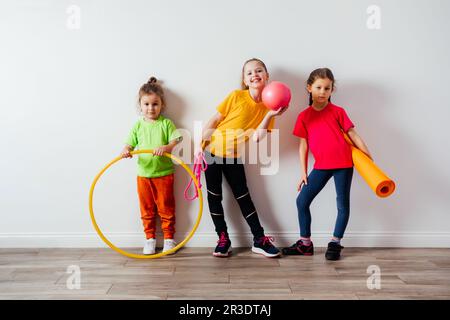 Sportliche Kinder in bunten T-Shirts posieren mit Sportausrüstung Stockfoto