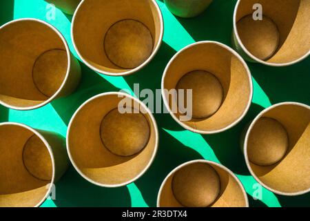 Leere recycelbare Pappbecher auf grünem Hintergrund. Viele Take-away-Becher zum Trinken. Umweltfreundlich. Zero Waste Kunststofffreies Konzept. Stockfoto