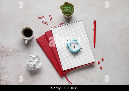 Leere Notebooks mit Mini-Wecker, Zimmerpflanzen und einer Tasse Kaffee auf grunge weißem Hintergrund Stockfoto