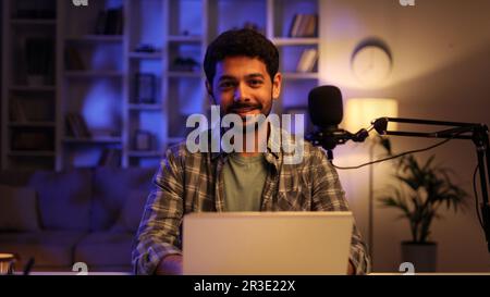 Porträt eines jungen, selbstbewussten Arabers, der Online-Computervideospiele spielt, zu Hause live streamt, lächelt und in die Kamera schaut. Gamer-Lifestyle, E Stockfoto