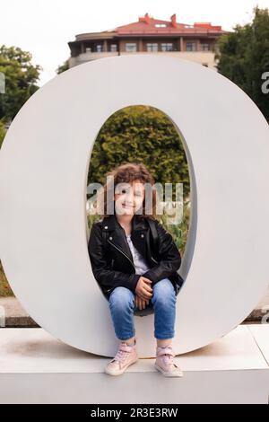 Das kleine Mädchen sitzt in dem großen Brief in der Stadt Stockfoto