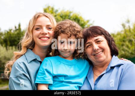 Nettes Mädchen umarmt Mutter und Großmutter im Freien Stockfoto