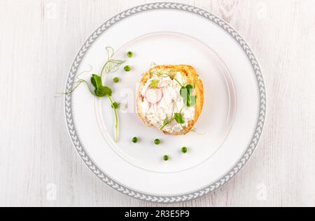 Leckeres Brot mit Frischkäse, Erbsen und Rettich auf weißem Teller von oben. Stockfoto