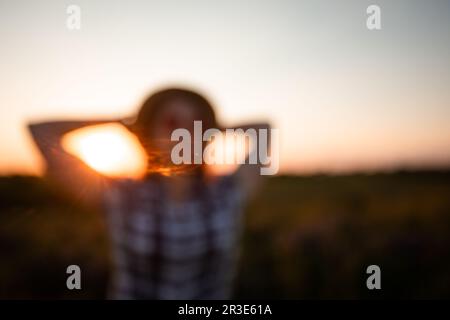 Verschwommenes Bild eines jungen Mädchens auf dem Hintergrund des Sonnenuntergangs Stockfoto