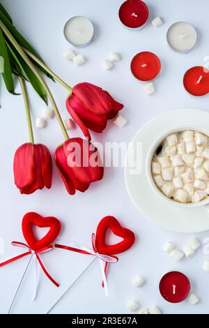 Platz für Text kopieren. Rote Tulpen Kerzen Weiße Tasse Kakao Marshmallows Frühstück. Urlaubshintergrund. Grußkarte. Va Stockfoto